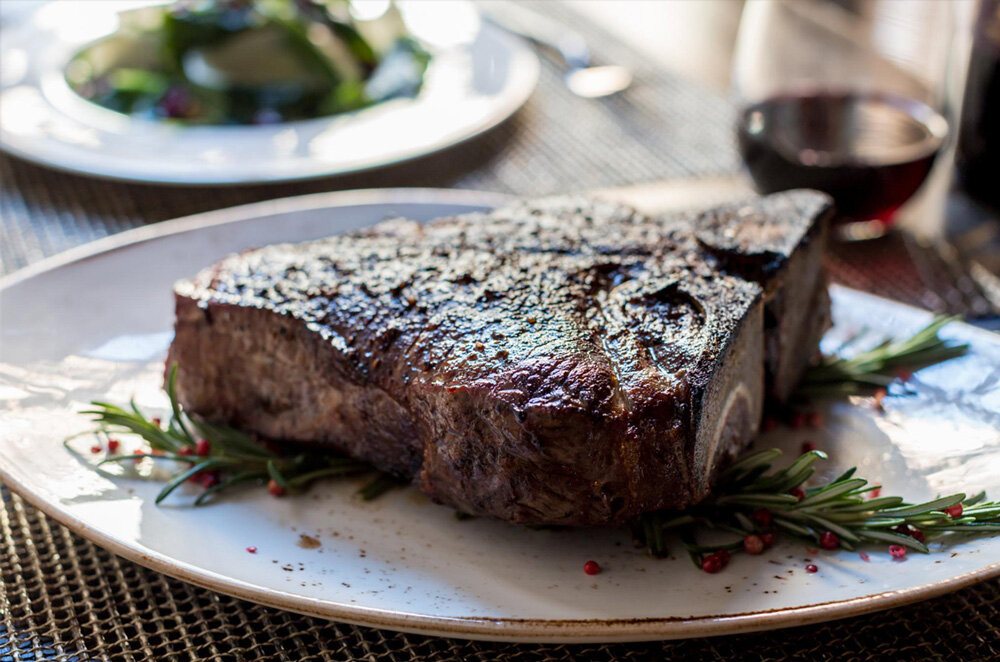 Dry-aged porterhouse steak plated with herbs