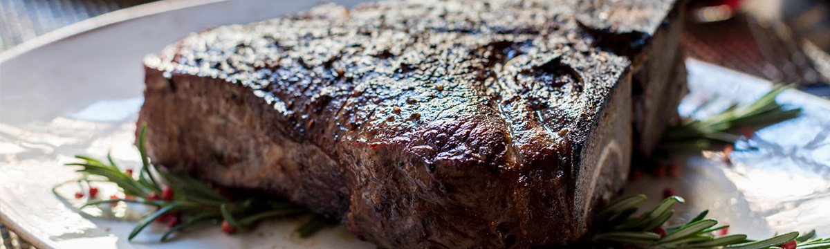 Ribeye steak resting with fresh herbs and peppercorns