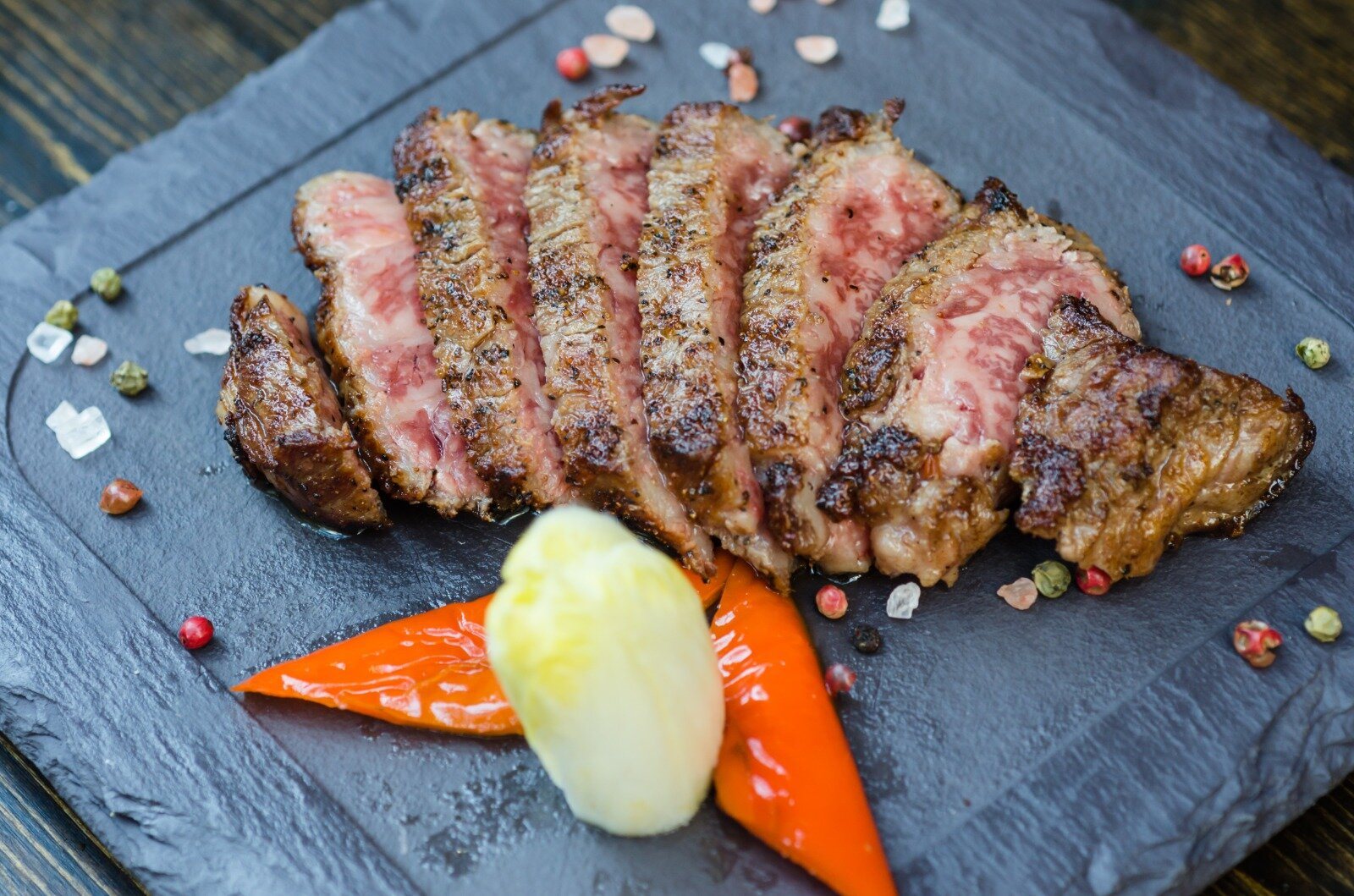 Sliced Wagyu steak arranged on slate showing marbling